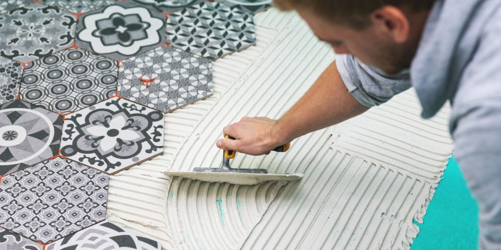 worker applying tile adhesive on the floor